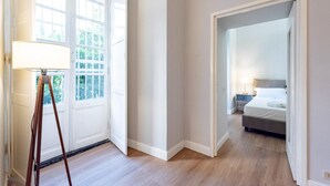 Une chambre d’hôtel avec un plancher en bois, un lit, une table de chevet et une lampe.