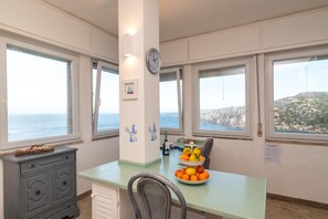 Een keuken met uitzicht op zee, een klok en een tafel met fruit.