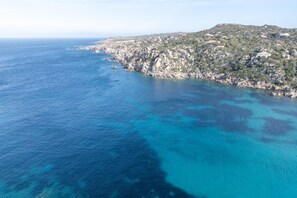 An aerial view of a coastal area with clear blue waters, rocky terrain, and scattered buildings. - Casa Alma in Santa Teresa di Gallura (Santa Teresa di Gallura)