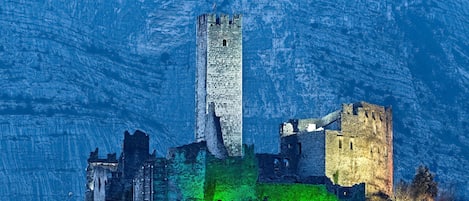 A historic castle with a prominent tower, surrounded by ruins and greenery.