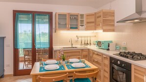 Una cucina moderna con mobili in legno, un piano cottura a gas e un'area pranzo con tavolo imbandito per quattro persone.