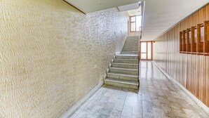A staircase with a textured wall on one side and a wooden panel wall on the other, leading to an upper floor. - Casa Arno 500m From Beach (Massa)