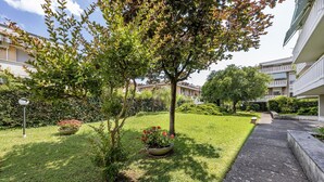 A courtyard with a paved walkway, a small tree, and a flower bed. - Casa Arno 500m From Beach (Massa)