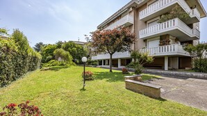 A multi-story residential building with balconies, a well-maintained lawn, and a street lamp. - Casa Arno 500m From Beach (Massa)