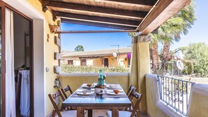 A balcony with a wooden table set for dining, a bottle, and bowls. - Dimora di Rosy Pittulongu (Olbia)
