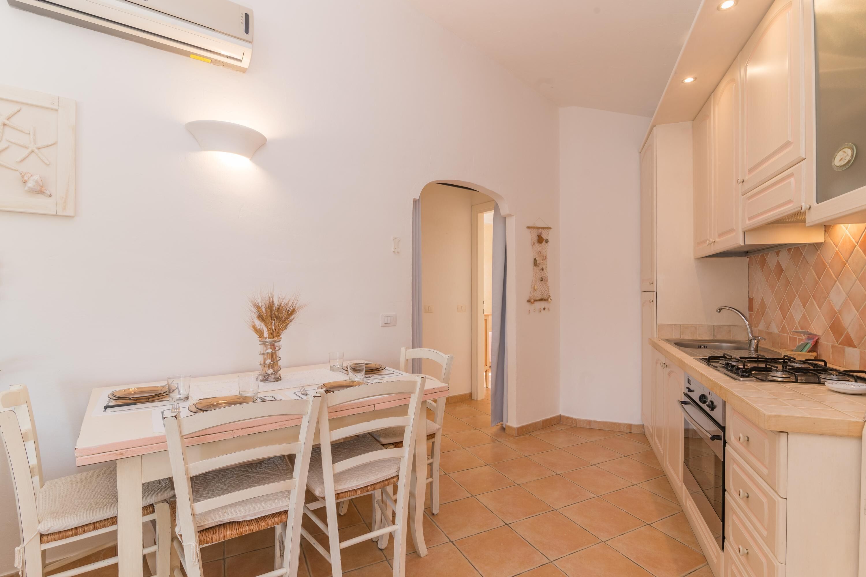 A kitchen with a dining table set for four, a stove, and a tiled backsplash.