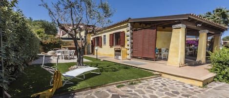 A house with a stone patio, a small lawn, and a pergola.
