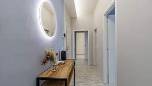 A hallway with a wooden bench, a vase with flowers, and a wall-mounted mirror. - Bedo House Beach Front (Follonica)