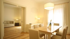 Un salon moderne avec une table à manger en bois, des chaises beiges, un canapé et une lampe.