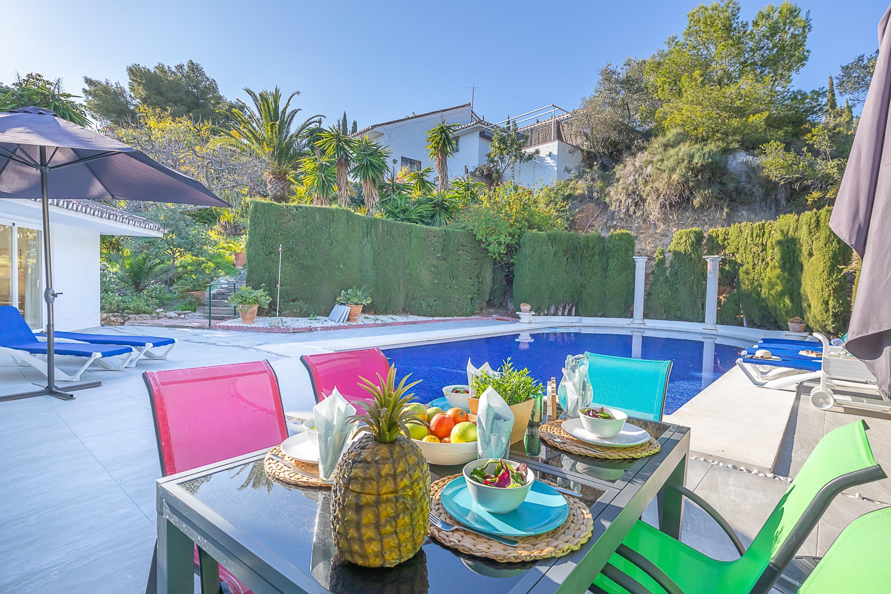 A poolside dining area with a table set for two, surrounded by lounge chairs and a clear view of the pool.