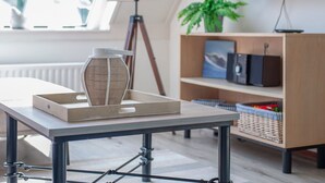 En moderne stue med et bord, en lampe, et fjernsyn og en reol.