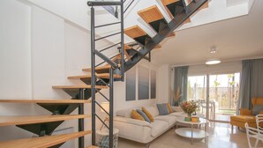 A modern living room with a wooden staircase, a sofa set, a coffee table, and a view of the outdoors. - Family Duplex Riviera With Pool (Mijas)