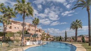 A swimming pool surrounded by palm trees and a building with balconies. - Family Duplex Riviera With Pool (Mijas)
