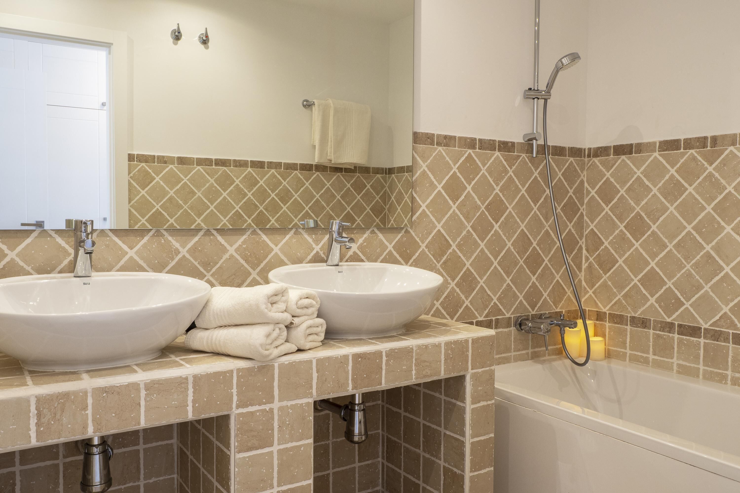 A bathroom with two sinks, a mirror, a shower, and a towel rack.