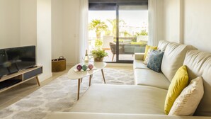 Un salon moderne avec un canapé, un téléviseur et une petite table agrémentée d’objets décoratifs.