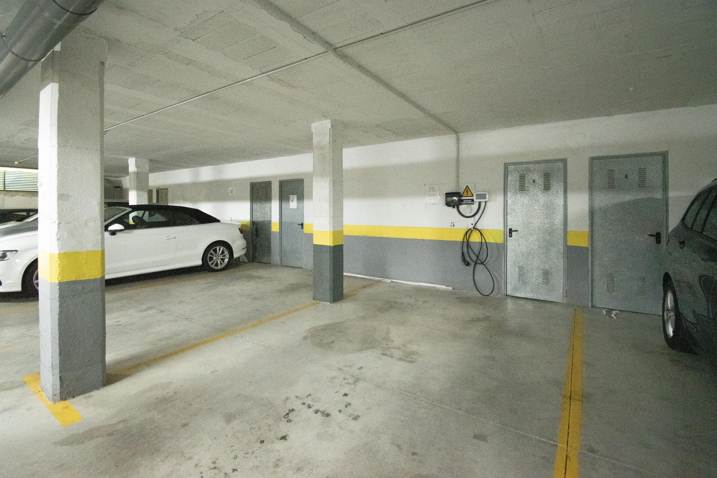 Eine Parkgarage mit Betonpfeilern, gelben Markierungen und Schließfächern.