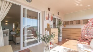 Ein großzügiger Wohnbereich mit einer Schiebetür zum Balkon, einer Couch, einem Couchtisch und einer Topfpflanze.