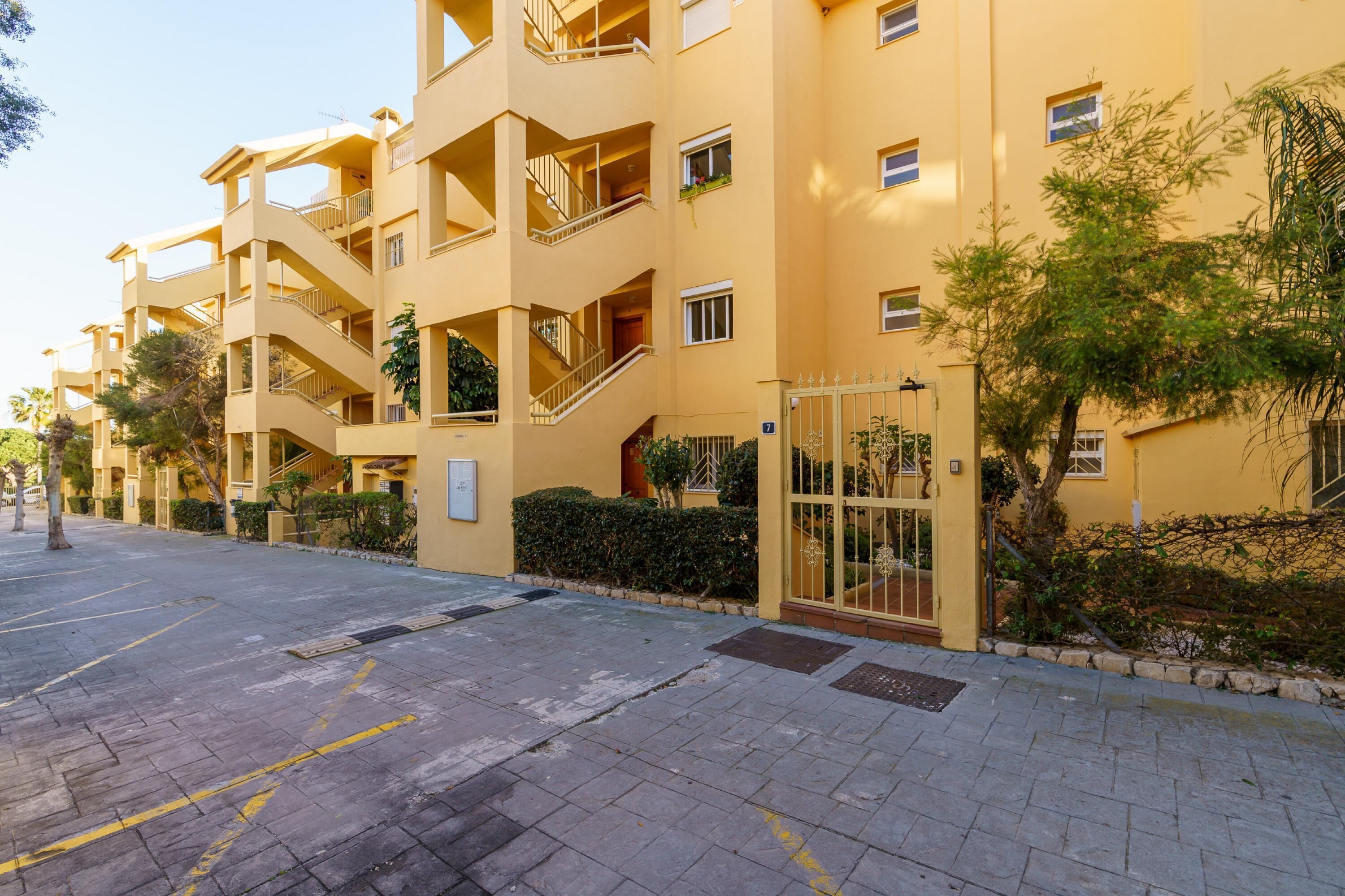 Un immeuble résidentiel à plusieurs étages, doté de balcons, d’une entrée sécurisée et d’une allée pavée.