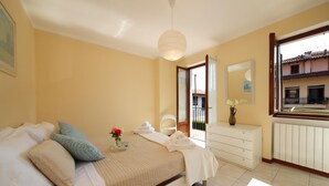 Een slaapkamer met een bed, nachtkastje en uitzicht op het balkon.