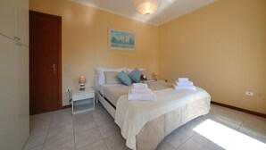 Een slaapkamer met een bed, nachtkastjes, een hanglamp en een schilderij aan de muur.