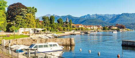 A waterfront area with boats docked, a stone wall, and buildings with red roofs.
