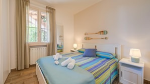 Une chambre d’hôtel avec un lit, deux tables de chevet, une fenêtre avec des rideaux et une planche de paddle fixée au mur.