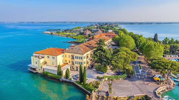 Un hôtel situé sur la côte, avec vue sur le front de mer, un parking et une promenade bordée d’arbres.