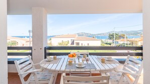 A balcony with a table set for breakfast, overlooking a coastal town. - La Lampara House in Cannigione (Arzachena)