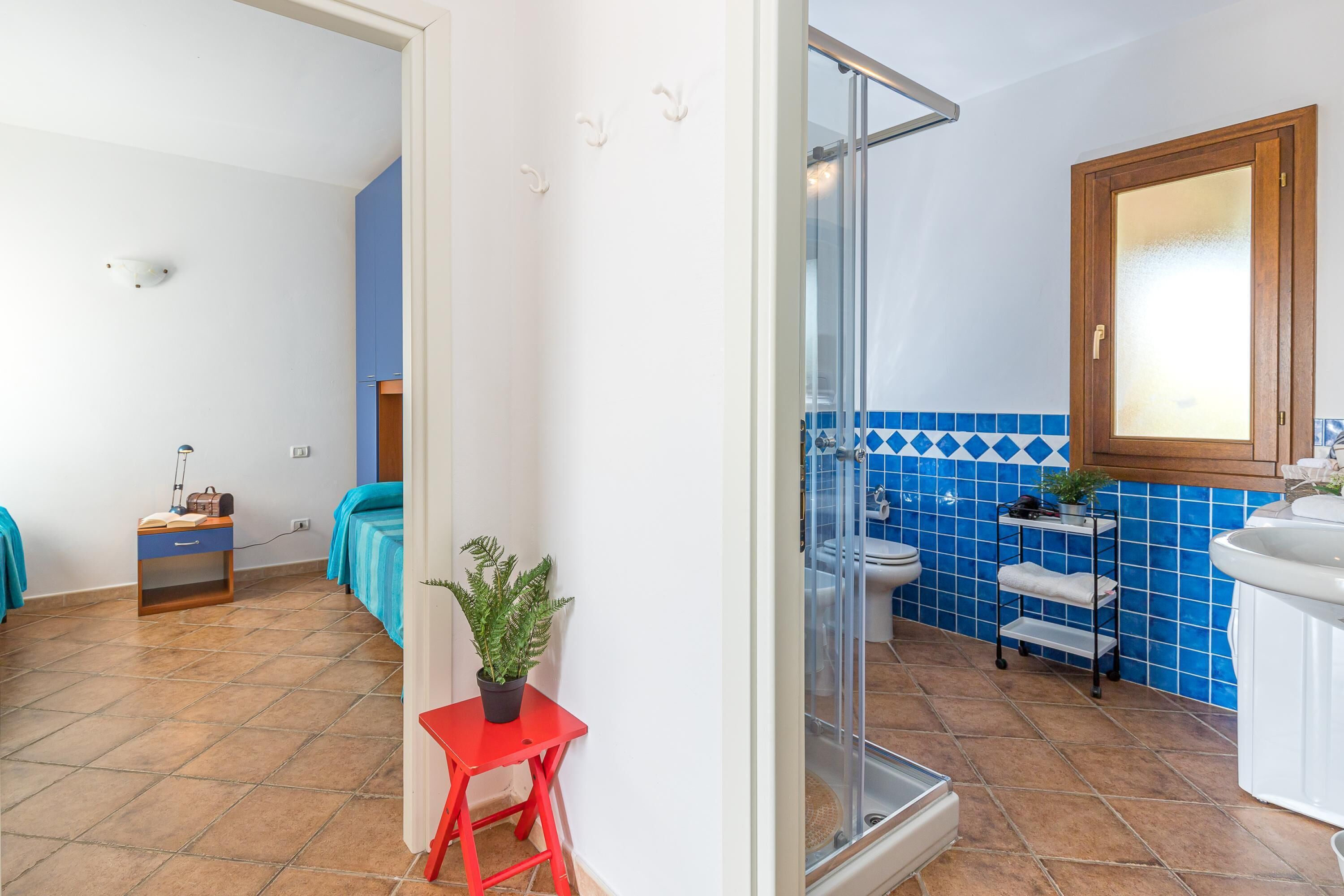 A bathroom with a glass shower enclosure, a white sink, and blue-tiled walls.