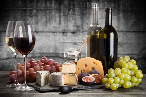 A selection of cheeses, grapes, and wine bottles on a wooden surface.