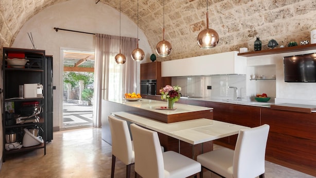 Une cuisine moderne dotée d’une arche en pierre, de luminaires suspendus et d’un îlot central avec des sièges.