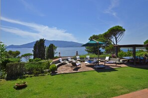 Eine Terrasse mit Gartenmöbeln, einer Pergola und Blick auf das Meer und die Berge.