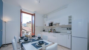 Eine moderne Küche mit weißen Schränken, einer Mikrowelle und einem Kühlschrank. Ein Esstisch ist gedeckt mit Tellern, Schüsseln und Besteck.