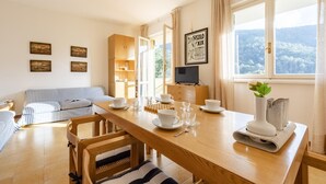 A cozy living room with a wooden dining table set for four, a striped sofa, and a television on a stand. - Peaceful Apartment In Deiva Marina (Deiva Marina)