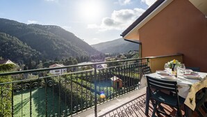 A balcony with a table set for dining, overlooking a lush valley and mountains. - Peaceful Apartment In Deiva Marina (Deiva Marina)