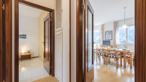 A hallway leading to a dining area with wooden furniture and a view of a snowy landscape through the window. - Peaceful Apartment In Deiva Marina (Deiva Marina)