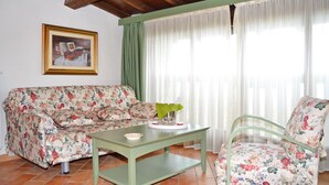 Un salon avec un canapé à motifs floraux, une table basse verte et un fauteuil à motifs floraux.