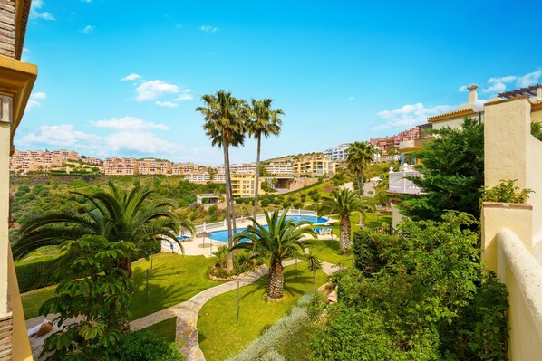 Un resort con piscina, palmeras y vistas a una colina con edificios.