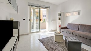 A modern living room with a flat-screen TV, a sofa, a coffee table, and a bookshelf. - Monopoli Beach House (Monopoli)