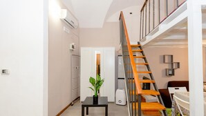 Un intérieur moderne avec un escalier, une petite table agrémentée d’une plante et une armoire blanche.