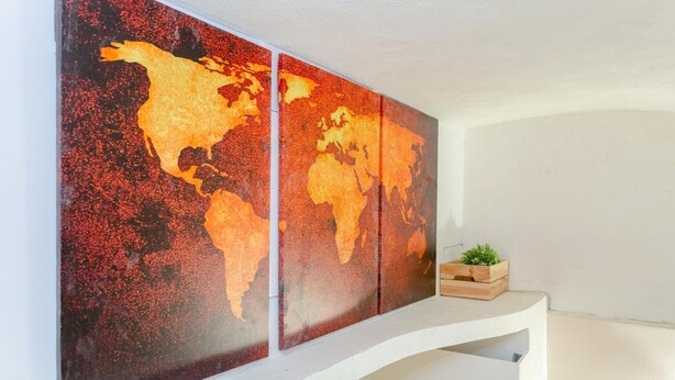 Une carte du monde décorative, fixée au mur, dans une pièce dont le plafond est blanc et qui est dotée d’une étagère intégrée.