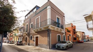 Un immeuble résidentiel à plusieurs étages, doté de balcons, avec des voitures garées et donnant sur la rue.