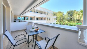 A balcony with a table and chairs, overlooking a building with multiple windows and a garden. - Rivoltella Apt With Pool 600m From Lake (Desenzano del Garda)