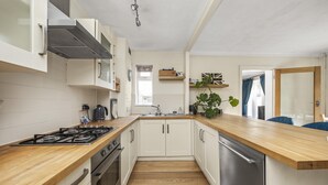 A modern kitchen with white cabinets, a wooden countertop, stainless steel appliances, and a window providing natural light. - Secret Garden House With Free Parking By My Getaways (Horsham)