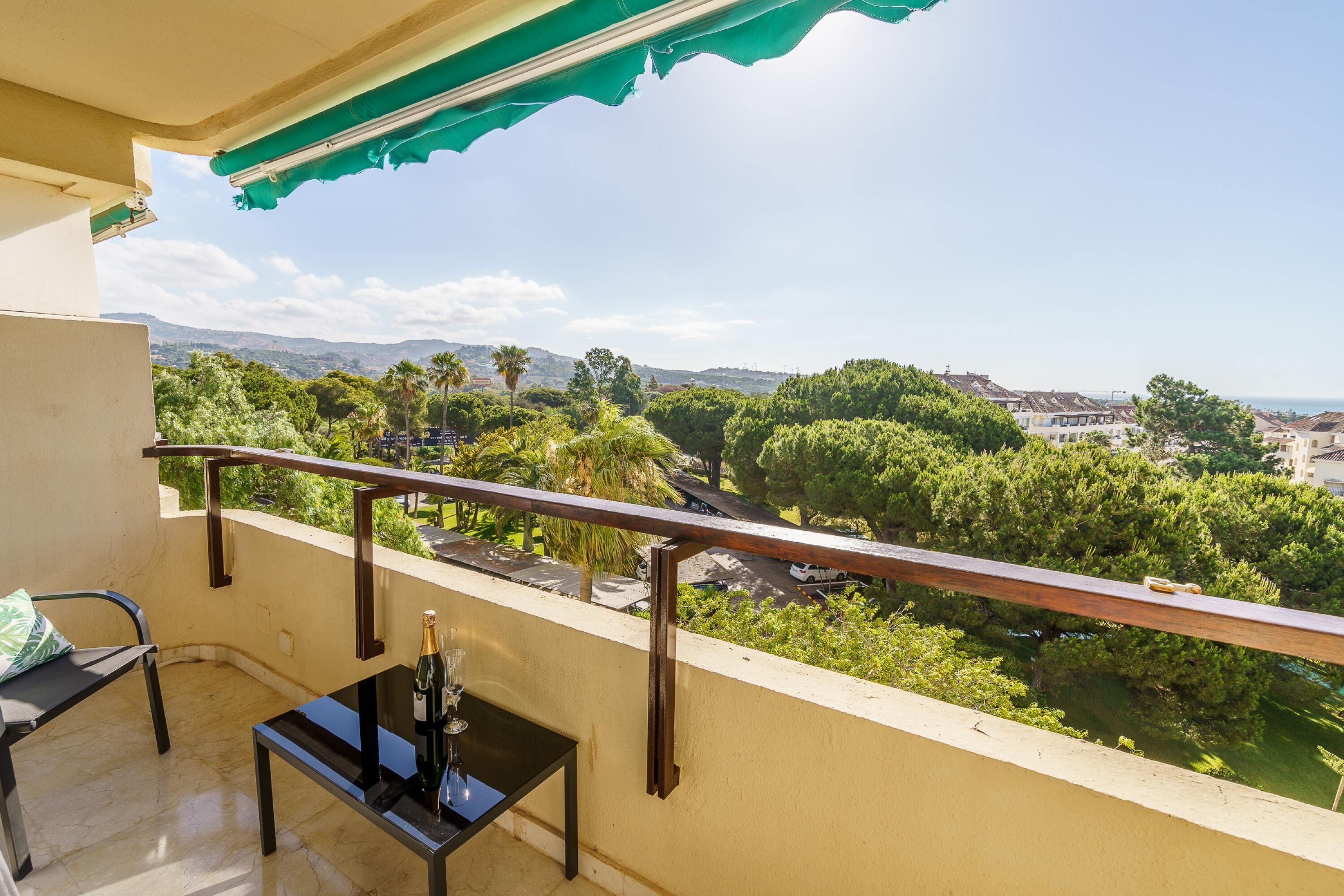 A balcony with a view of a river, trees, and distant buildings.