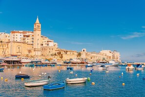 A harbor with boats and a historic building with a tower. - Exceptional Sunlit Apart Marsaskala Bay (Marsaskala)