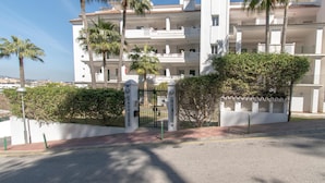 A multi-story building with balconies, palm trees, and a gated entrance. - Rancho Miraflores in Las Lagunas de Mijas (Mijas)