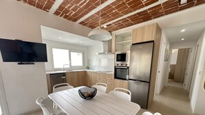 A modern kitchen with white cabinetry, a stainless steel refrigerator, and a built-in oven. - Arago 273 in Roses With 2 Bedrooms and 2 Bathrooms (Roses)