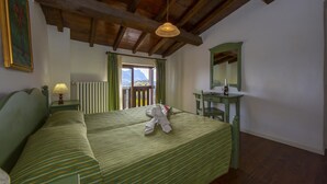 A room with a bed, a desk, a chair, a lamp, a radiator, and a window with a view of mountains. - Violetta in Hilly Area (Gargnano)