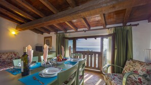 A dining area with a table set for four, a sofa, and a view of the sea. - Violetta in Hilly Area (Gargnano)